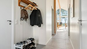 A hallway with a shoe rack, coat hooks, and a view into a room with a table and chairs.