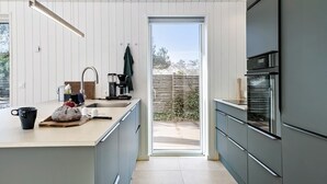 A modern kitchen with a large island, a built-in oven, and a sliding glass door leading to a patio.