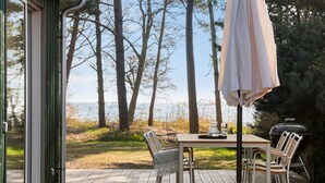 An outdoor deck with a table and chairs, a grill, and an umbrella.