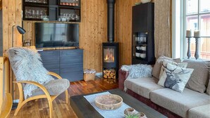 A cozy living room with a stone fireplace, wooden furniture, and a TV.