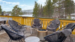 A deck with wicker chairs and a round table, overlooking a snowy landscape.