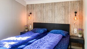 A double bed with a wooden headboard, two bedside tables, and a wall-mounted light fixture. - Awesome home in Andijk with WiFi (Andijk)