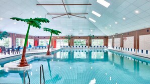 An indoor swimming pool with clear blue water, surrounded by a tiled deck. There are two palm trees and a lifeguard stand visible. - Awesome home in Andijk with WiFi (Andijk)