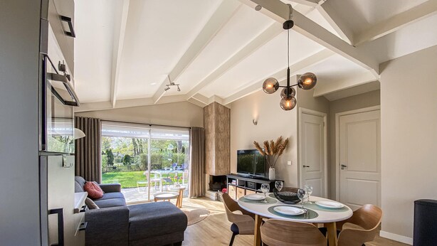 A modern living room with a sofa, dining table, and TV. There is a sliding glass door leading to a garden. - Awesome home in Andijk with WiFi (Andijk)