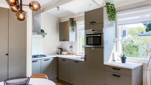 A modern kitchen with grey cabinets, a stainless steel oven, and a window with a view of greenery. - Awesome home in Andijk with WiFi (Andijk)