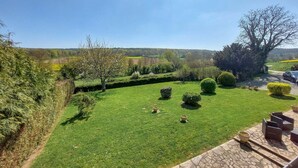 Un jardín bien cuidado con setos ordenados, diversas especies de árboles y una vista despejada del campo circundante.