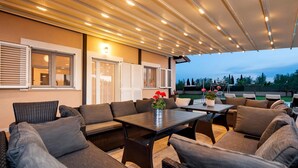 An outdoor patio with wicker furniture, a table with a vase of flowers, and a view of the garden. - Gorgeous home in Rovinj (Rovinj)
