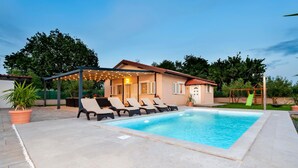 A swimming pool with lounge chairs, a covered patio, and a small building with shutters. - Gorgeous home in Rovinj (Rovinj)