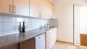Eine moderne Küche mit hellen Holzschränken, einer Edelstahl-Spüle und einem Geschirrspüler.