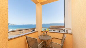 Ein Balkon mit Tisch und Stühlen und Blick auf die Küste.