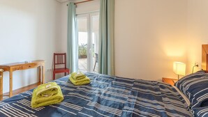 Un dormitorio con cama, escritorio, silla y vistas al exterior.