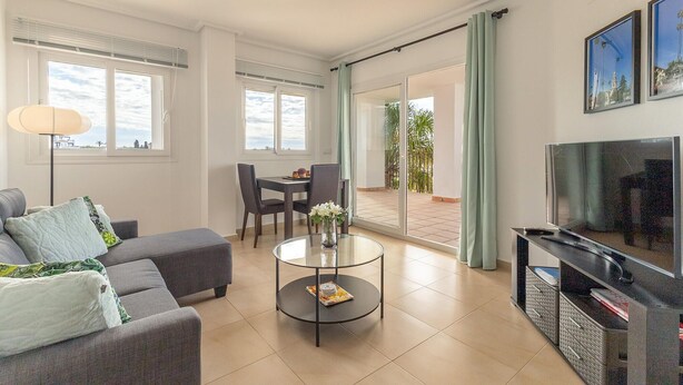 Una sala de estar moderna con un sofá, una mesa de centro, un televisor y un balcón con vistas.