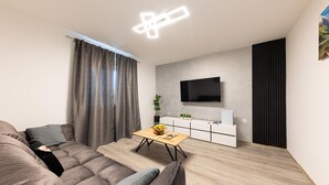 A modern living room with a sofa, a coffee table, a flat-screen TV mounted on the wall, and a small potted plant. - Awesome home in Blato na Cetini (Blato na Cetini)