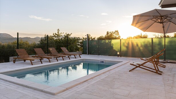 A swimming pool with lounge chairs and an umbrella, surrounded by a fence and greenery. - Awesome home in Blato na Cetini (Blato na Cetini)