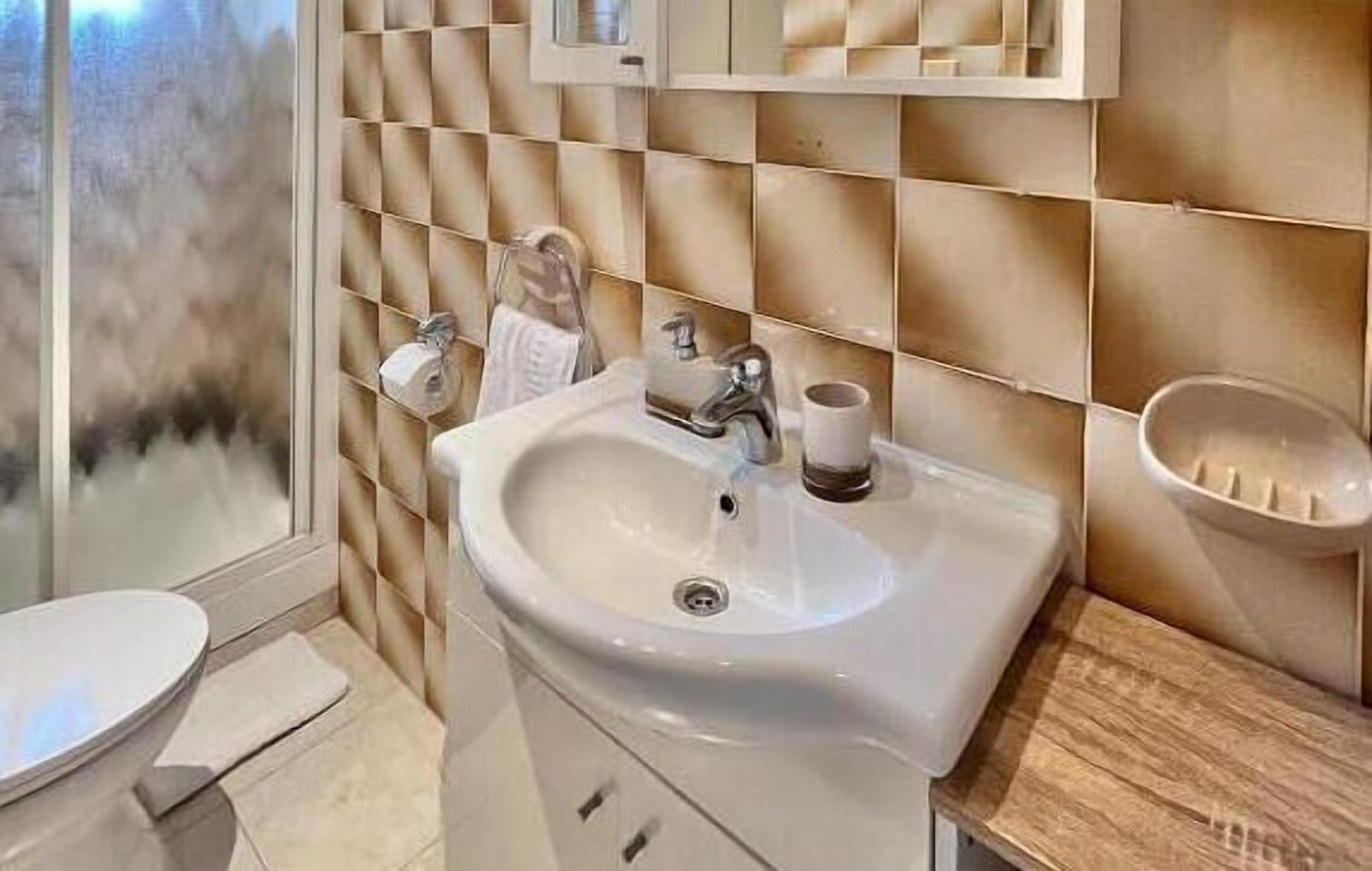 Ein Badezimmer mit einem weißen Waschbecken, einem Spiegel darüber und einer Holzausstattung.