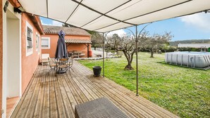 A covered patio with a wooden deck, outdoor furniture, a table, and a barbecue grill. - Comfortable, pittoresques (Combas)