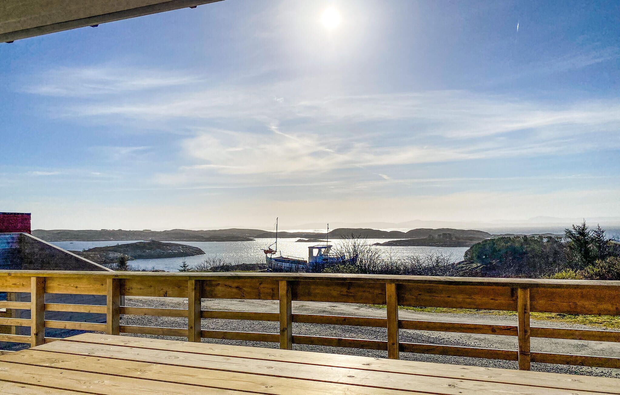 A wooden deck overlooking a calm body of water with a distant island and hills.