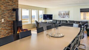 Een moderne woonkamer met een grote open haard, leren banken, een eettafel en een televisie.