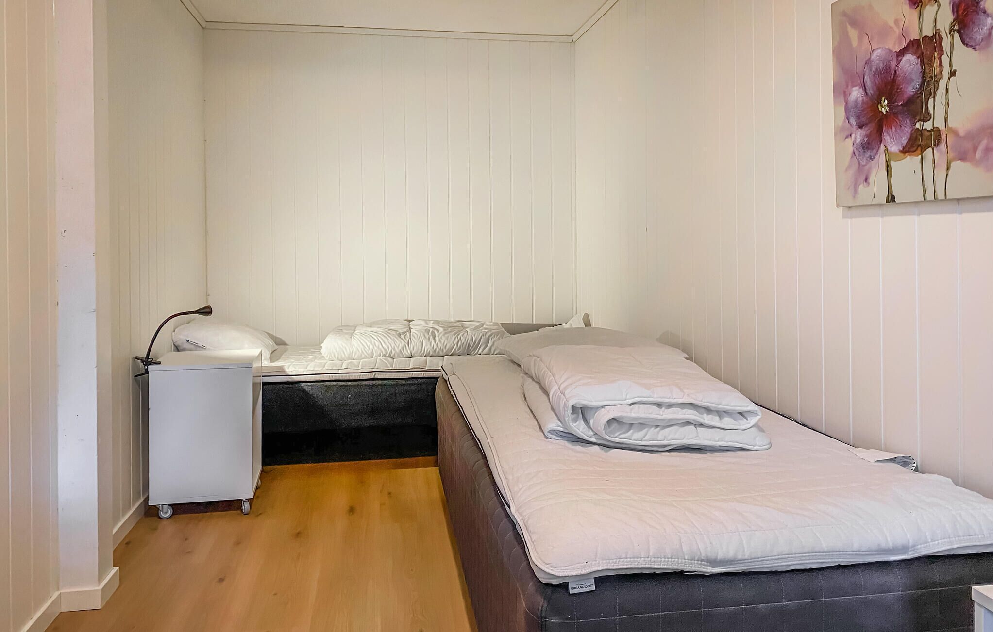 Une petite chambre à coucher, bien rangée, avec un lit simple, une table de chevet et une commode.