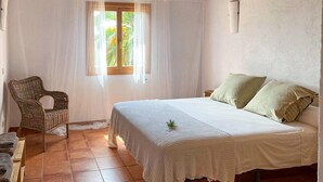 A bedroom with a bed, a chair, and a window with curtains. - Nice home in Son Servera (Son Servera)