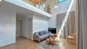 Una sala de estar moderna con un sofá gris, un televisor y una mesa de centro de madera.