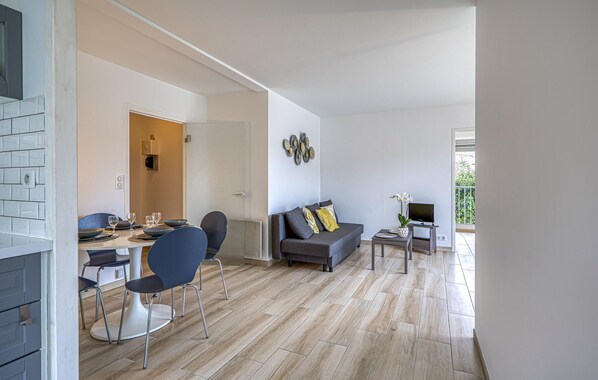 A modern living room with a dining area, a sofa, a TV, and a small table with a plant.