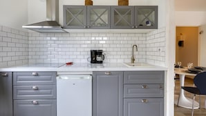 A kitchen with grey cabinets, a coffee maker, and a dishwasher.
