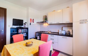 Een koelkast, een oven, een kookplaat, kookgerei, borden en bestek