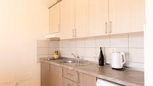 A kitchen with light wooden cabinets, a stainless steel sink, a white kettle, and a bottle of wine. - Amazing apartment in Duce with house sea view (Duce)