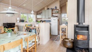 A cozy kitchen with wooden cabinets, a central island, a built-in stove, and a dining area with chairs and a table.