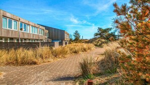 Un edificio moderno con un sendero pavimentado que lo conduce, rodeado de vegetación natural.