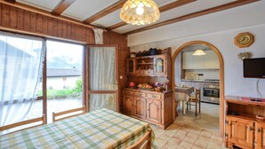 Een gezellige keuken met houten kastjes, een eettafel met geruit tafelkleed, en uitzicht op het landschap door een raam.