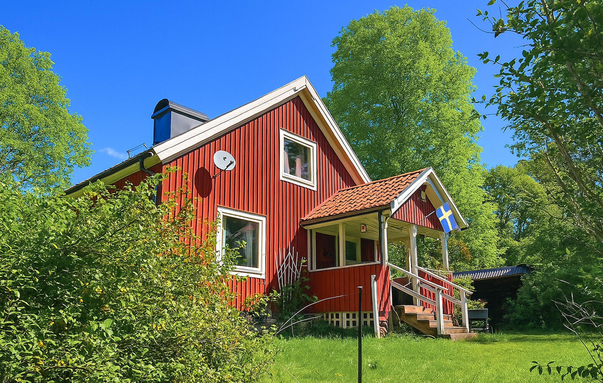 Une maison en bois rouge avec un porche et un drapeau.