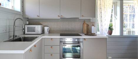 A compact kitchen with a built-in oven, a microwave, and a sink.