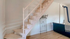 Una escala de fusta amb barana metàl·lica, un sofà blau i una paret blanca.