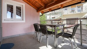 Un patio techado con una mesa, sillas, una ventana y vistas de un edificio residencial.