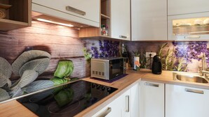 Cocina moderna con microondas integrado, estufa y pileta. Hay muebles de cocina y una mesada con plantas decorativas.