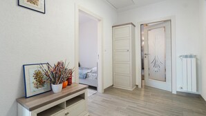 Una habitación con piso de madera, paredes blancas, un cuadro en la pared, un escritorio con un jarrón de flores y un radiador.