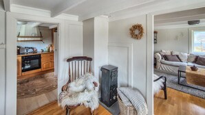A cozy living area with a sofa, a chair, a fireplace, and a kitchen visible through an open door. - Amazing home in Nedre Vats with house sea view (Nedre Vats)