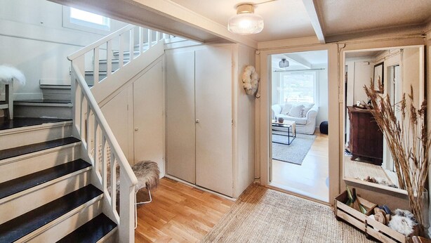 A staircase leading to a second floor, a living area with a sofa and a coffee table, and a wooden crate with bottles and decorative items. - Amazing home in Nedre Vats with house sea view (Nedre Vats)