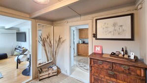 A room with a wooden dresser, a mirror, a framed botanical print, and a door leading to a kitchen. - Amazing home in Nedre Vats with house sea view (Nedre Vats)