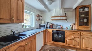 A kitchen with wooden cabinets, a dishwasher, a stove, and a microwave. - Amazing home in Nedre Vats with house sea view (Nedre Vats)