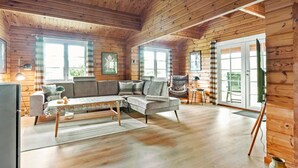 A cozy cabin interior with a wooden interior, a sofa, a chair, and a dining table.