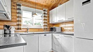 A modern kitchen with white cabinets, a built-in dishwasher, a microwave, and a coffee maker.