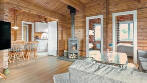 A cozy cabin interior with a dining area, kitchen, and a fireplace.