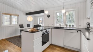 A modern kitchen with white cabinetry, a black countertop, and a wooden island. There are two pendant lights, a Bosch oven, and a Bosch dishwasher. - Awesome home in Nexø with sauna (Nexø)