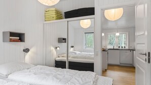 A bedroom with a bed, bedside tables, a wardrobe, and a small kitchenette. - Awesome home in Nexø with sauna (Nexø)