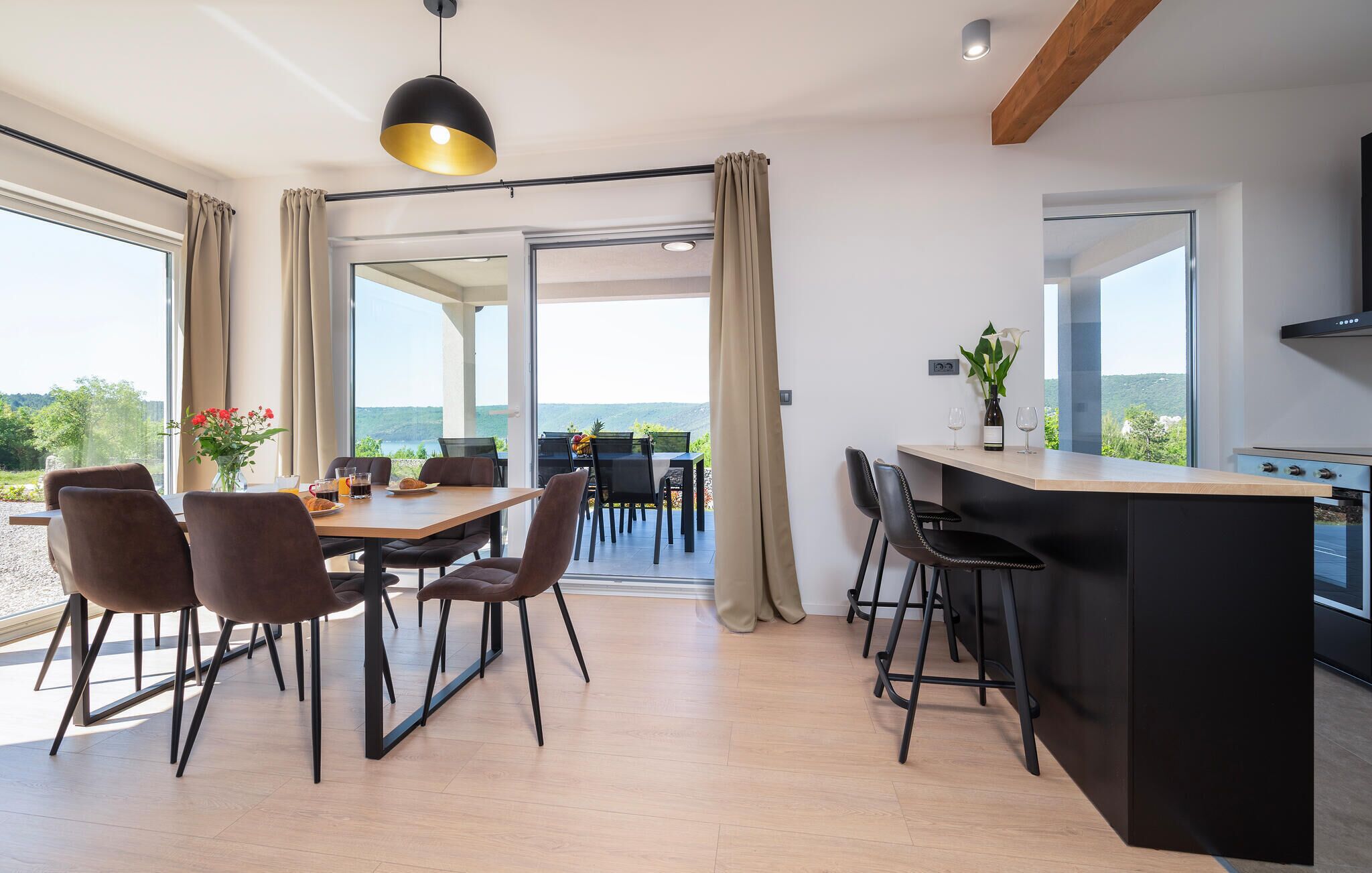 Eine moderne Küche mit Bar, Essbereich und großen Fenstern mit herrlichem Ausblick.