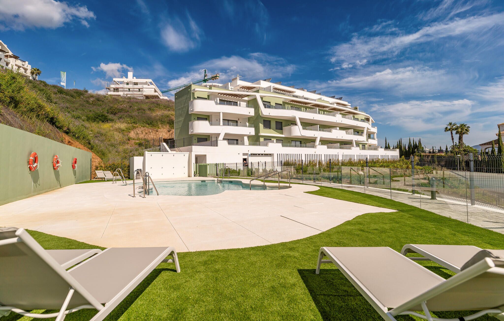 Ein modernes Hotel mit Pool, mehreren Balkonen und einem gepflegten Rasen.