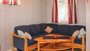 A corner living room with a dark blue sofa, two wooden chairs, a wooden coffee table, and a patterned cushion. - Nice apartment in Sälen with sauna (Sälen)